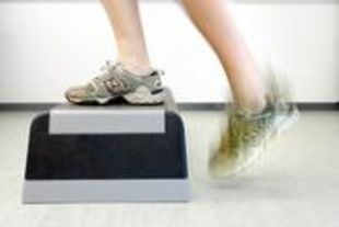 Füße in Sportschuhen beim Auf- und Absteigen auf Podest beim Steptest