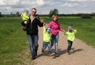 Eltern mit drei kleinen Kindern auf einem Spaziergang.